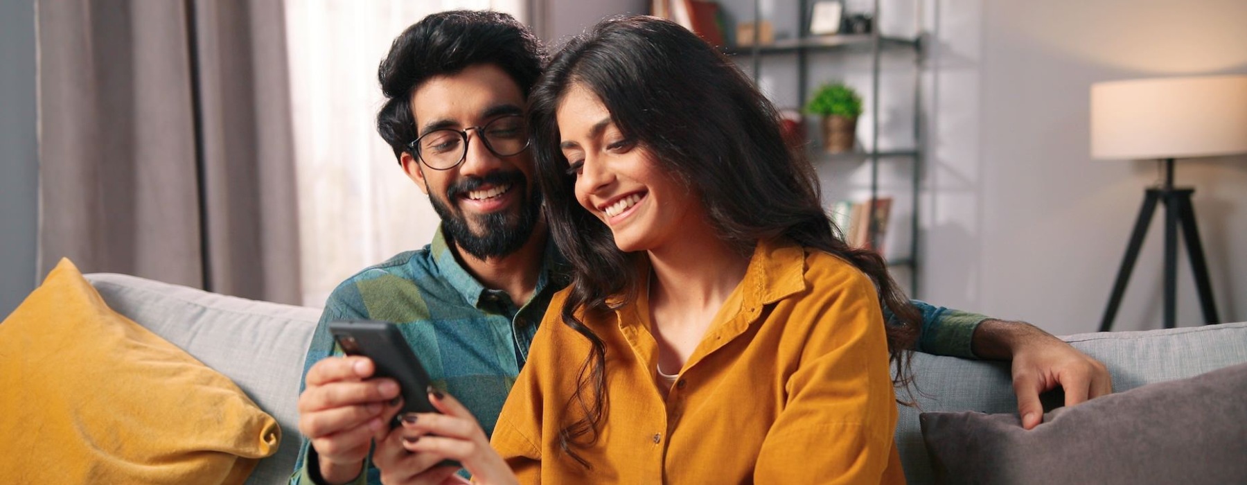 a couple looking at a cell phone on a sofa