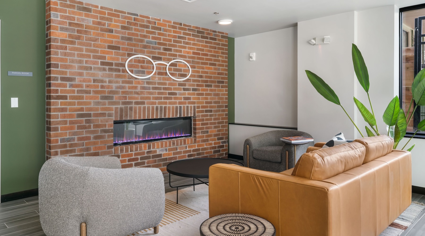 a clubroom with a couch, chair and a fireplace