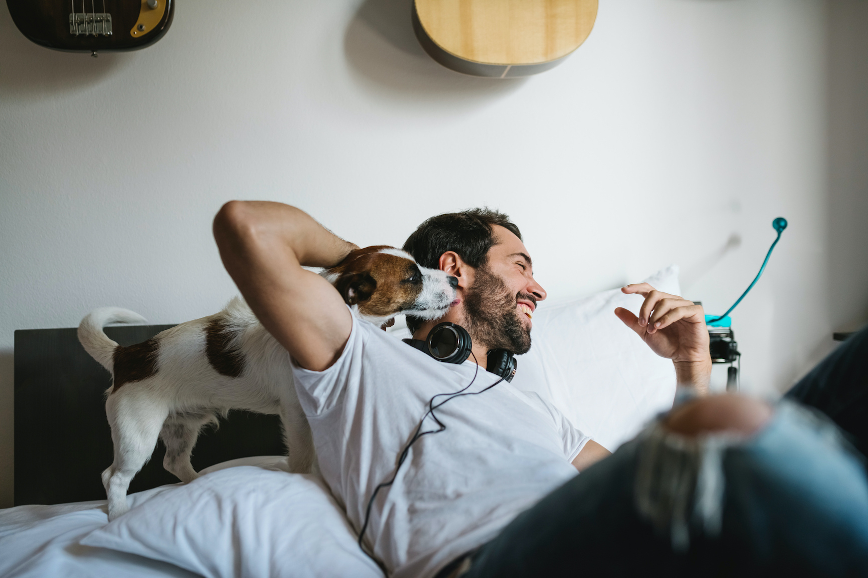 Smiling man playing with puppy in an open floorplan apartment that includes stainless steel appliances and luxury options.